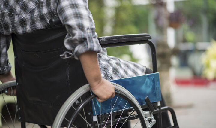 Close-up of senior woman hand on wheel of wheelchair during walk in hospital